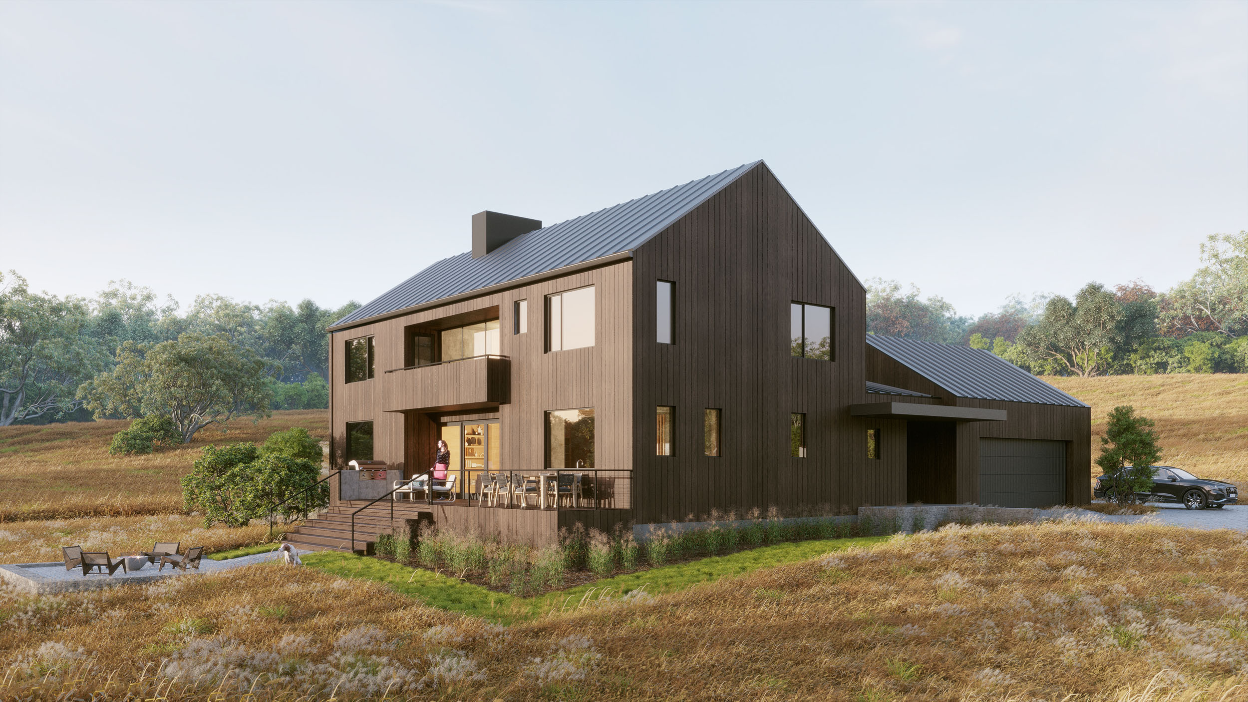 Modern two-story residence featuring dark vertical wood siding, a standing-seam metal gable roof, and an elevated deck with outdoor dining overlooking an open meadow landscape