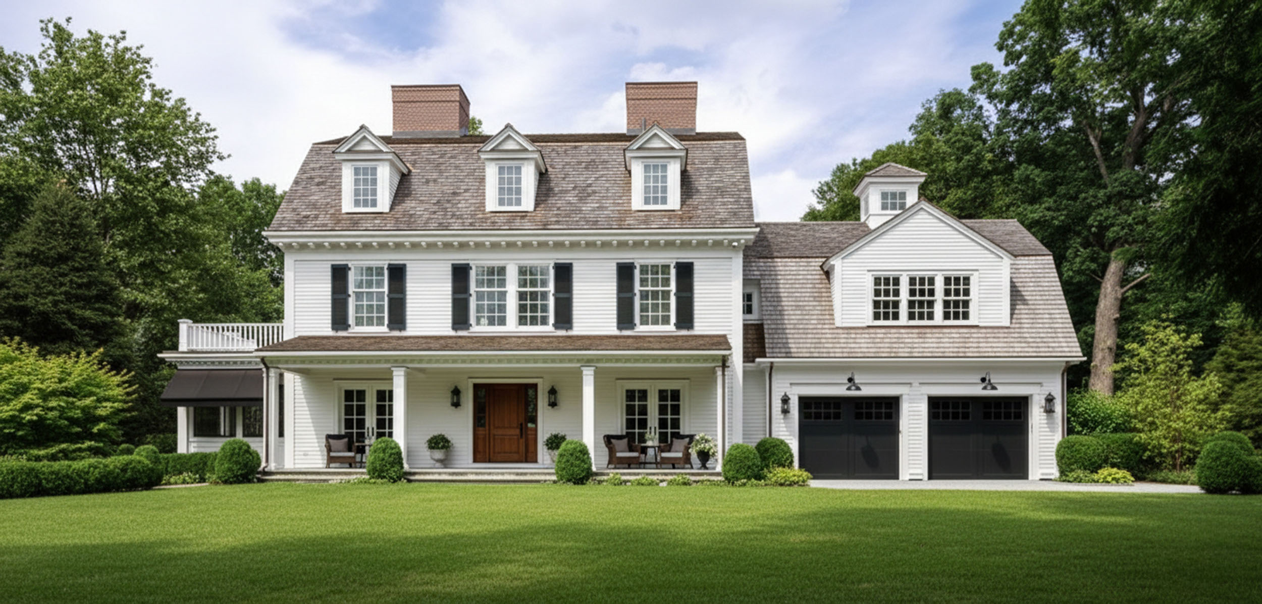 Classic Colonial style home featuring white clapboard siding, black window shutters, dormer roof windows, and a covered front porch overlooking a manicured lawn