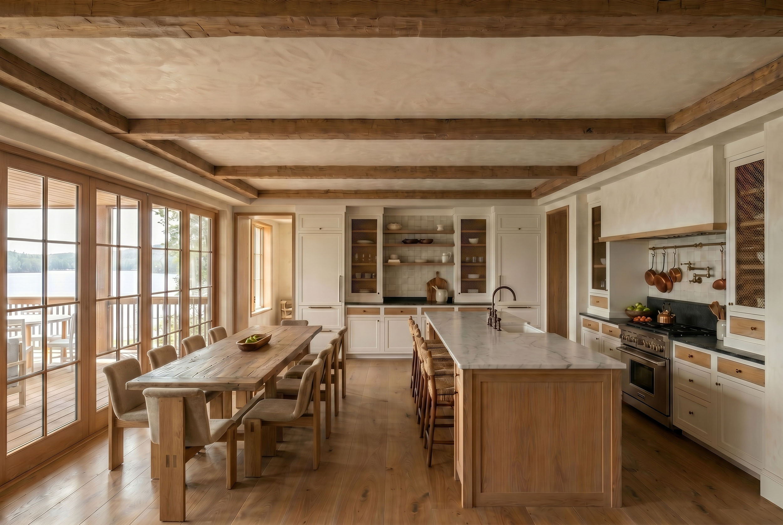 Open-concept kitchen and dining area featuring exposed wood ceiling beams, a marble island with woven barstools, custom white built-in cabinetry, and a rustic wooden dining table on hardwood floors